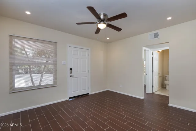 a view of an empty room with wooden floor and a window