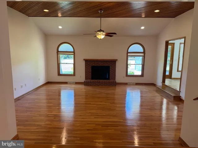 an empty room with wooden floor fireplace and windows