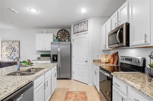 a kitchen with granite countertop stainless steel appliances a stove refrigerator sink and microwave