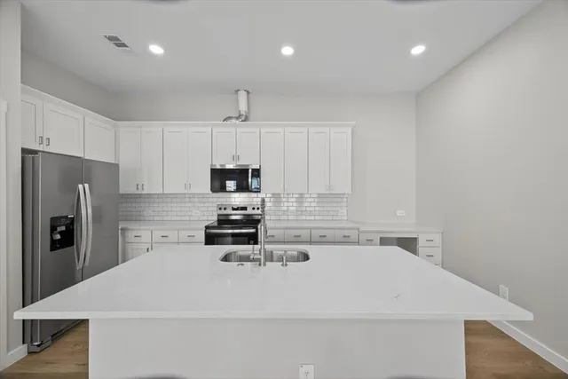 a kitchen with white cabinets and stainless steel appliances