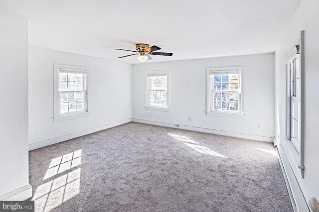 an empty room with windows and fan