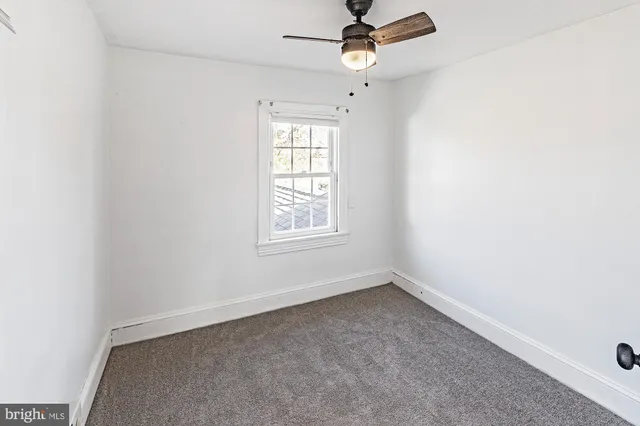 an empty room with a window and a ceiling fan