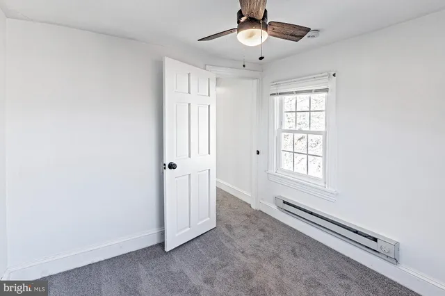 an empty room with windows and ceiling fan