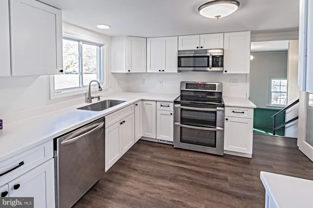 a kitchen with cabinets stainless steel appliances and wooden floor