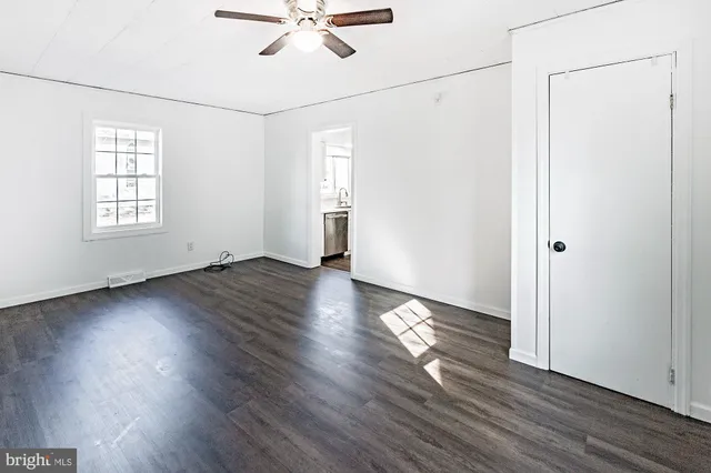 an empty room with wooden floor fan and windows