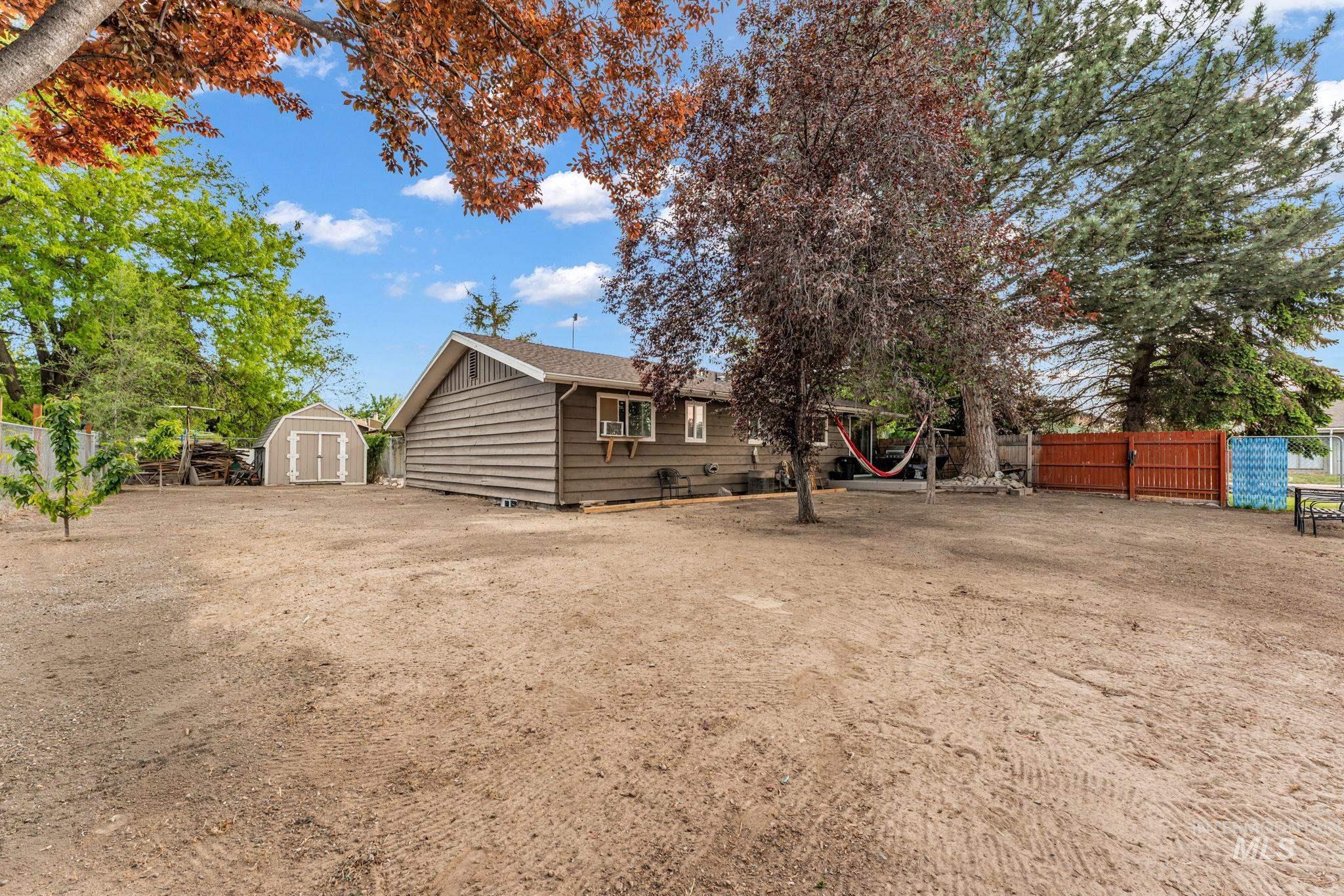 820 Meadows Drive Twin Falls, ID 83301 - Photo 35 of 38 Gravel side yard featuring a chain-link fence, mature trees, and a storage shed