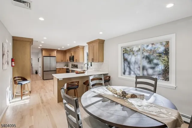 a kitchen with stainless steel appliances kitchen island granite countertop a stove a sink a refrigerator and white cabinets with wooden floor