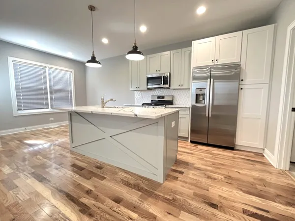 a kitchen with stainless steel appliances granite countertop a refrigerator a sink dishwasher a stove with white cabinets and wooden floor