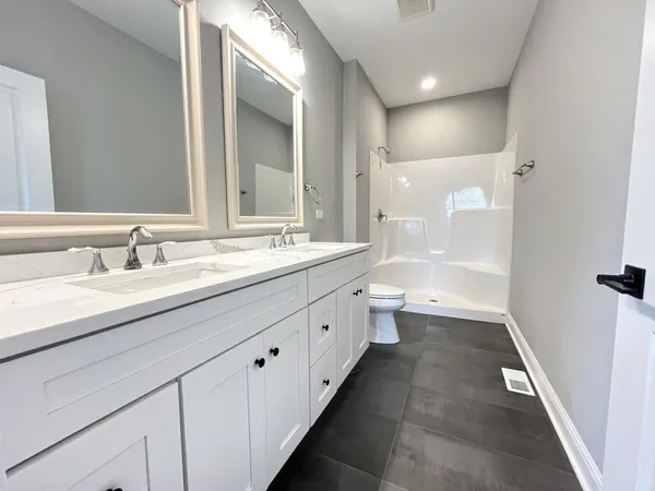 a spacious bathroom with a double vanity sink a mirror and a bathtub