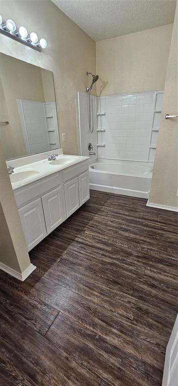 2820 Deer Ridge Drive Rockwall, TX 75032 - Photo 8 of 13 Double vanity with white cabinetry, wood-finish flooring, and a bath/shower combination with a white subway-style surround