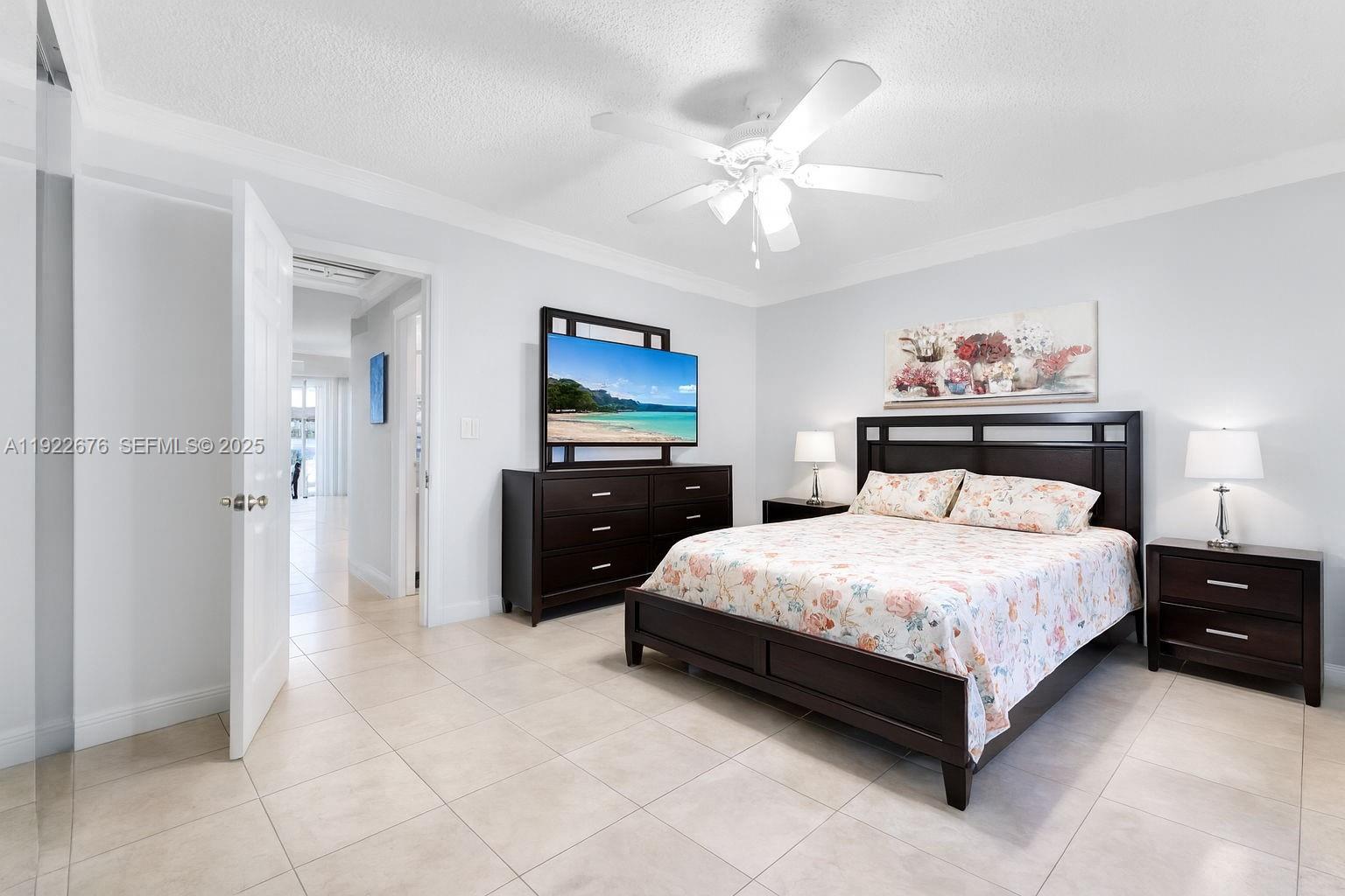 900 Atlantic Shores Boulevard, Unit 105 Hallandale Beach, FL 33009 - Photo 13 of 22 a spacious bedroom with a bed and a chandelier