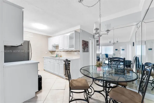 a kitchen with stainless steel appliances kitchen island granite countertop a dining table chairs and a refrigerator