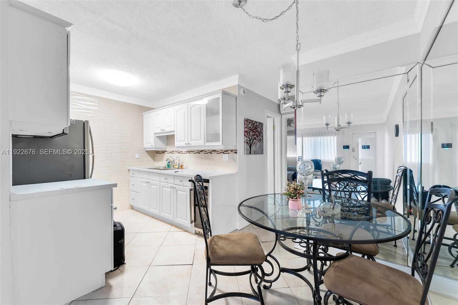 900 Atlantic Shores Boulevard, Unit 105 Hallandale Beach, FL 33009 - Photo 8 of 22 a kitchen with stainless steel appliances kitchen island granite countertop a dining table chairs and a refrigerator