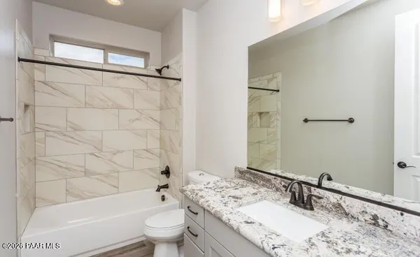 a bathroom with a granite countertop sink a toilet and shower