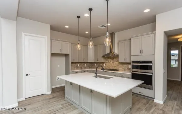 a kitchen with kitchen island a sink stainless steel appliances and white cabinets