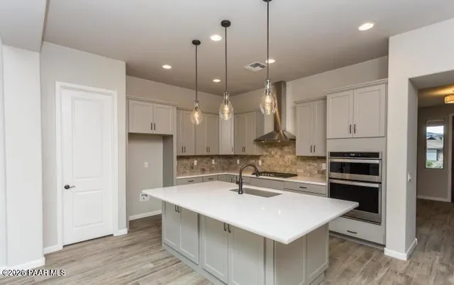 a kitchen with kitchen island a sink stainless steel appliances and white cabinets