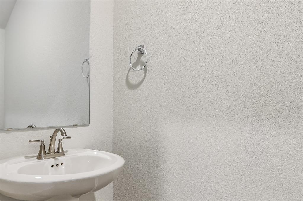 2808 Totley Road Manor, TX 78653 - Photo 6 of 21 Pedestal sink with a brushed nickel faucet set, large wall mirror, and a chrome towel ring