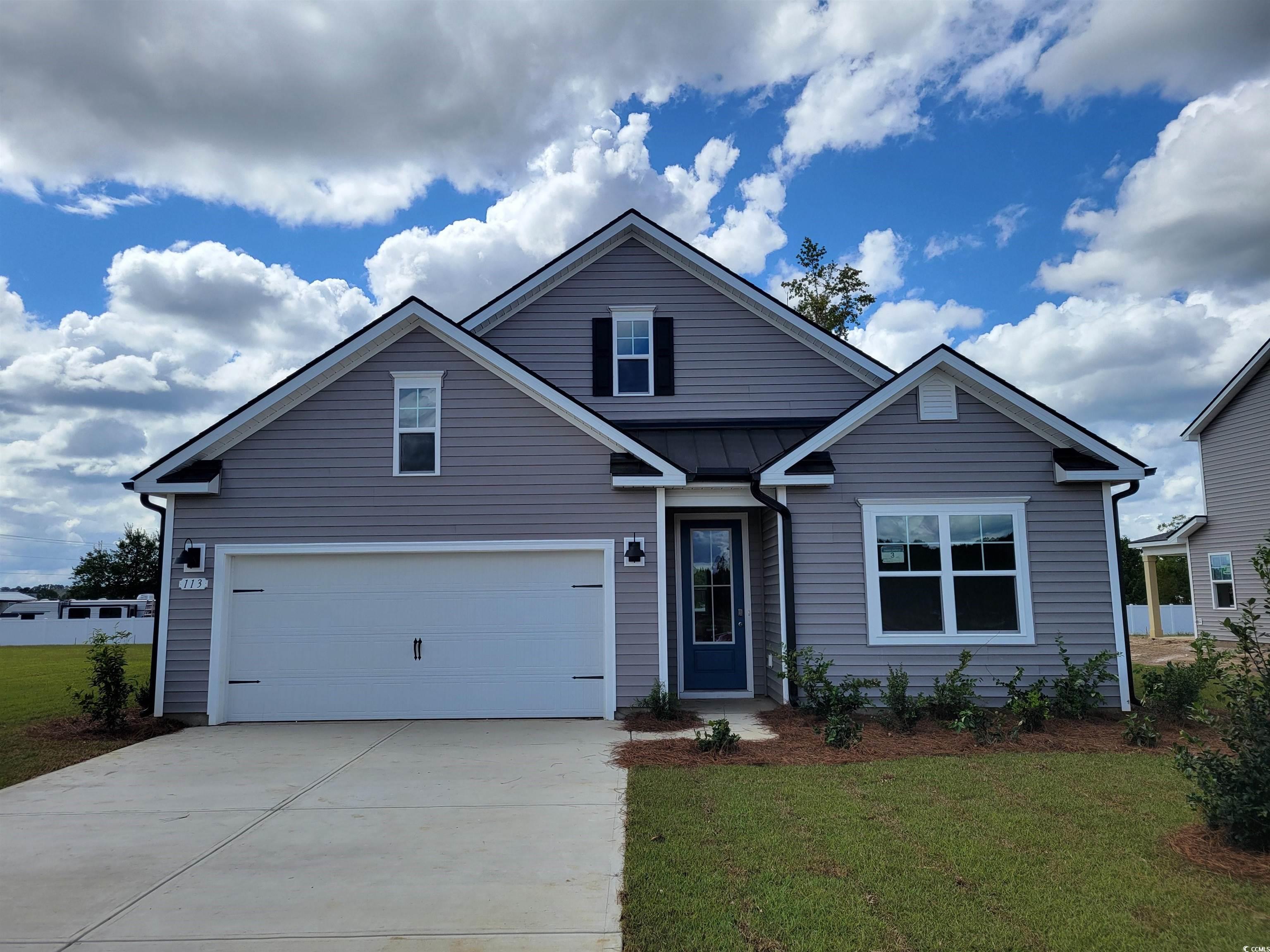 View of front facade featuring concrete driveway and a front lawn