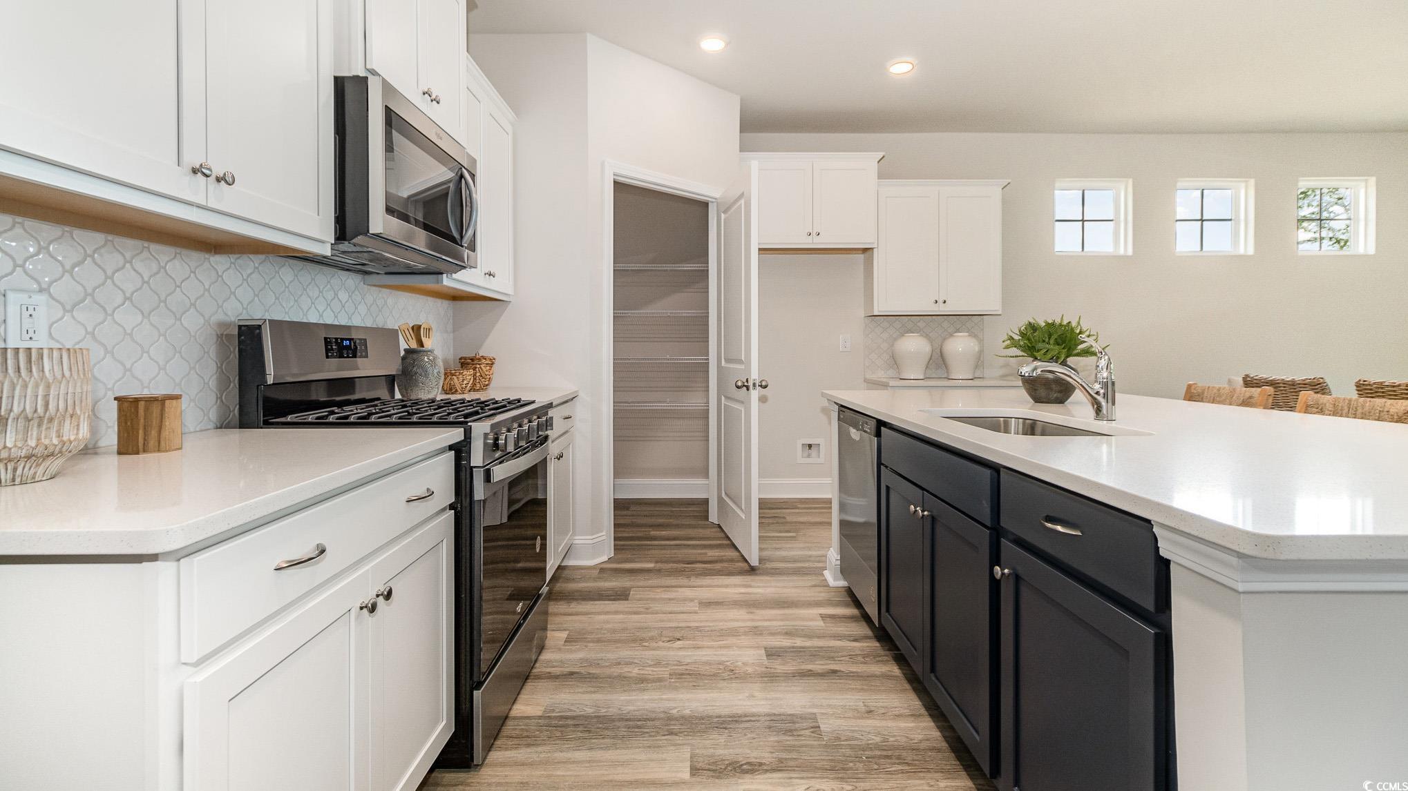113 Keithland Drive Conway, SC 29527 - Photo 10 of 24 Kitchen featuring appliances with stainless steel finishes, white cabinetry, light wood finished floors, backsplash, and light countertops