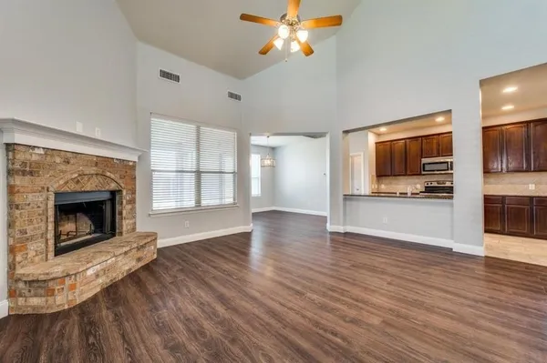a view of a kitchen and an empty room with wooden floor a fireplace