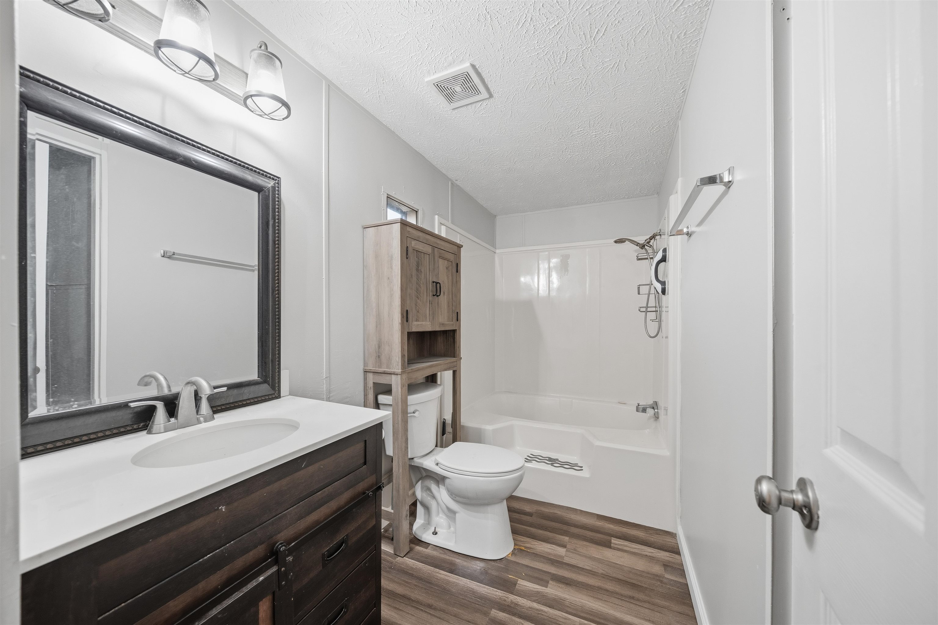 79 Stevens Road Mason, TN 38049 - Photo 11 of 21 Full bath with vanity, a textured ceiling, shower / washtub combination, and dark wood finished floors