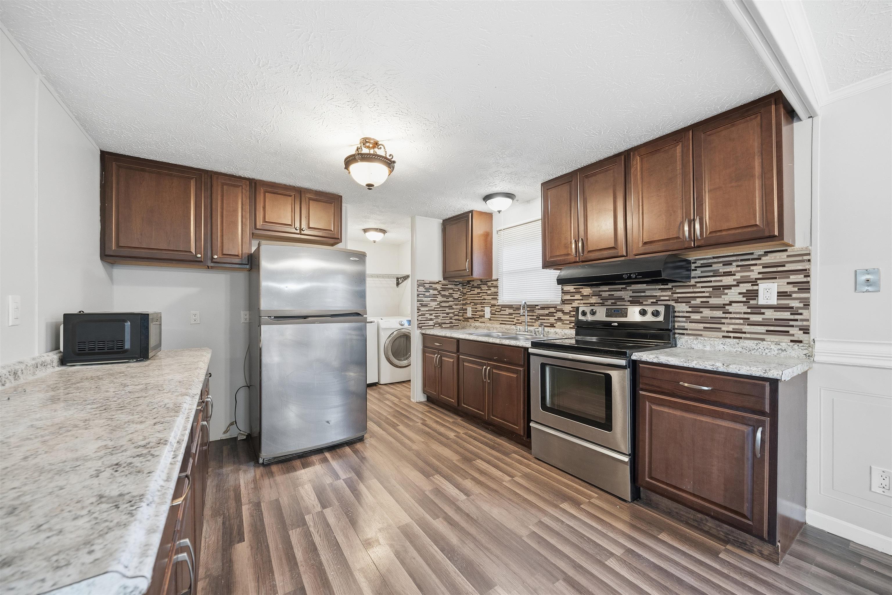 79 Stevens Road Mason, TN 38049 - Photo 7 of 21 a kitchen with granite countertop wooden floors stainless steel appliances and a sink