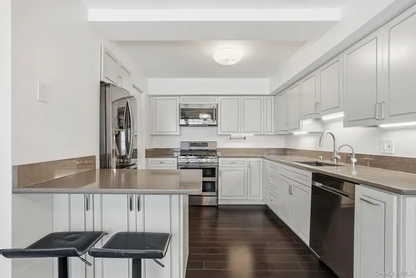 a kitchen with kitchen island granite countertop a sink cabinets and stainless steel appliances