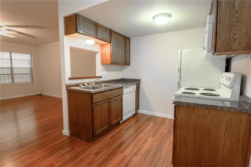 710 East Dean Keeton Street, Unit 207 Austin, TX 78705 - Photo 4 of 6 A well-appointed kitchen features warm wood cabinetry and durable countertops, flowing into an adjacent living space.