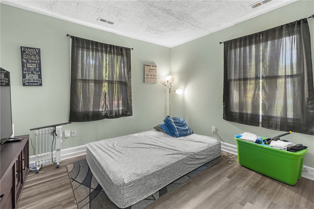 303 South Elm Street Pendleton, SC 29670 - Photo 6 of 16 This spacious bedroom offers ample natural light and durable flooring, creating a comfortable and inviting atmosphere.