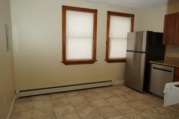 a view of a refrigerator in kitchen and an empty room