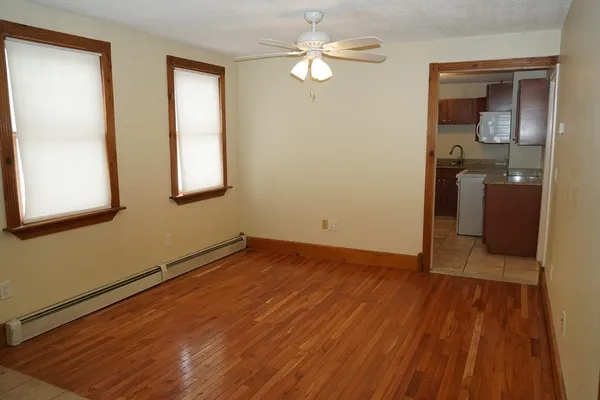 a view of empty room with wooden floor and fan