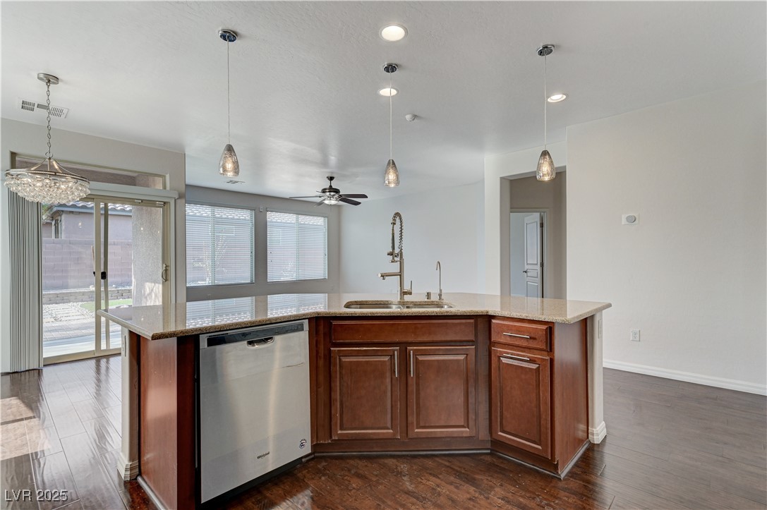 6946 Motley Road Las Vegas, NV 89178 - Photo 10 of 31 Kitchen featuring stainless steel dishwasher, a kitchen island with sink, light stone counters, dark wood-style flooring, and recessed lighting