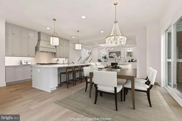 a dining room filled a chandelier and kitchen view