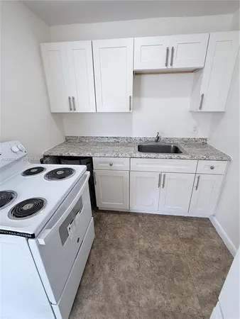 a kitchen with granite countertop a sink a stove and cabinets