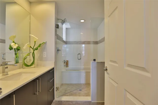 a bathroom with a granite countertop sink a mirror and a shower