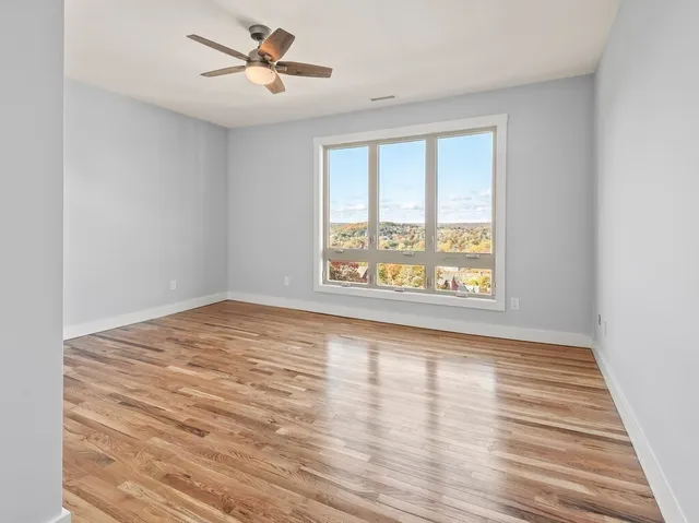 a view of an empty room with wooden floor and a window