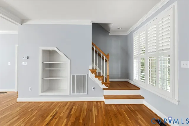 a view of an empty room with a window and wooden floor