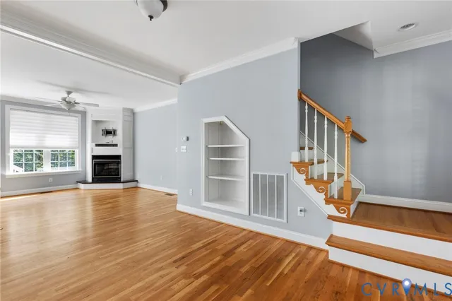 a view of an empty room with wooden floor fireplace and a window