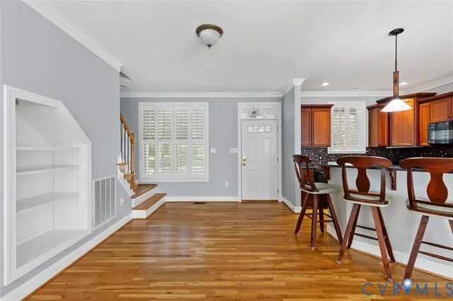 a kitchen with stainless steel appliances granite countertop a refrigerator a stove top oven a dining table and chairs with wooden floor