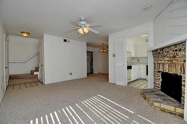 an empty room with windows fireplace and a kitchen view