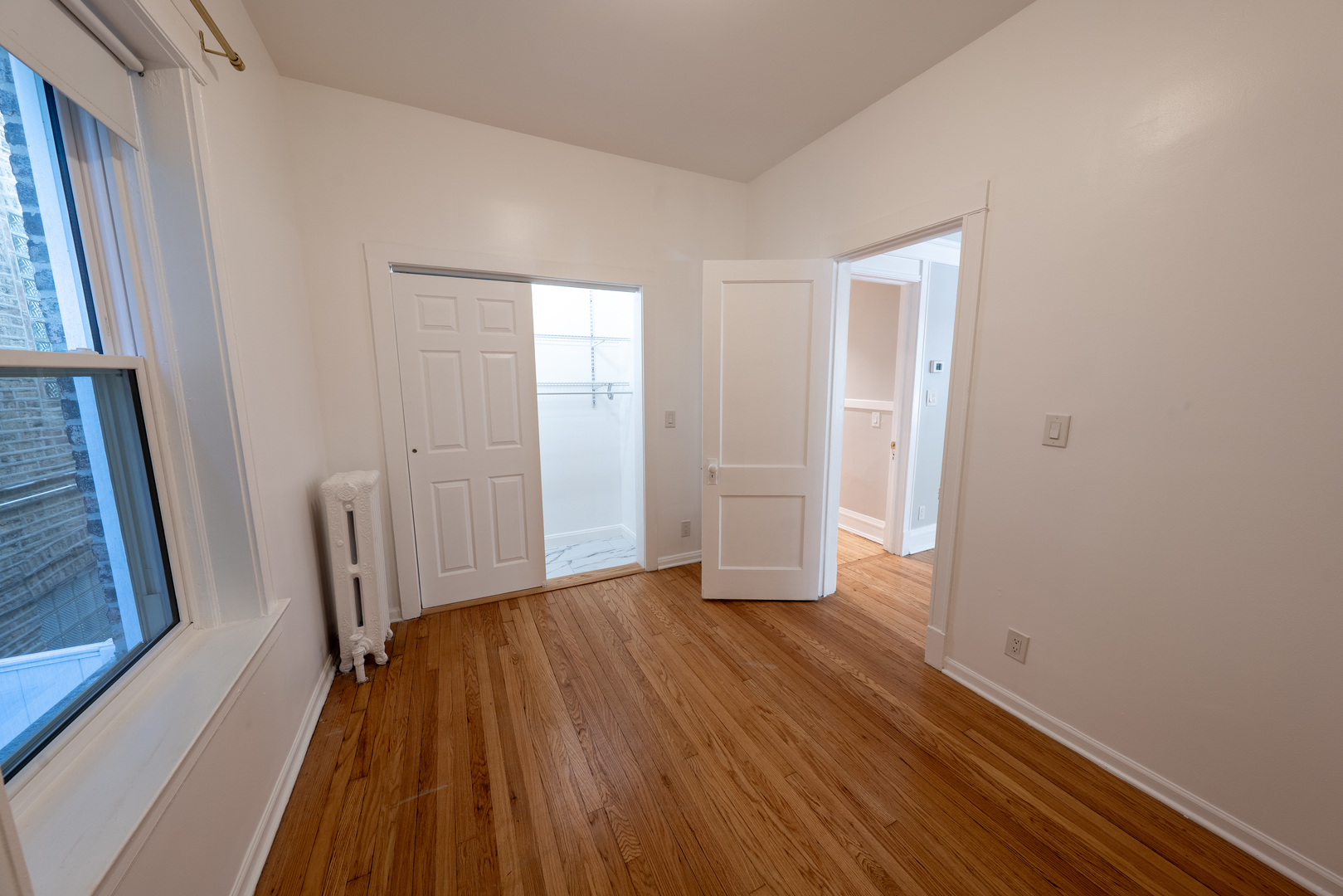 1460 West Foster Avenue, Unit 1 Chicago, IL 60640 - Photo 6 of 14 a view of an empty room with wooden floor and a window