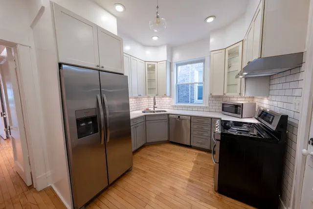 a kitchen with stainless steel appliances a refrigerator a sink cabinets and wooden floor