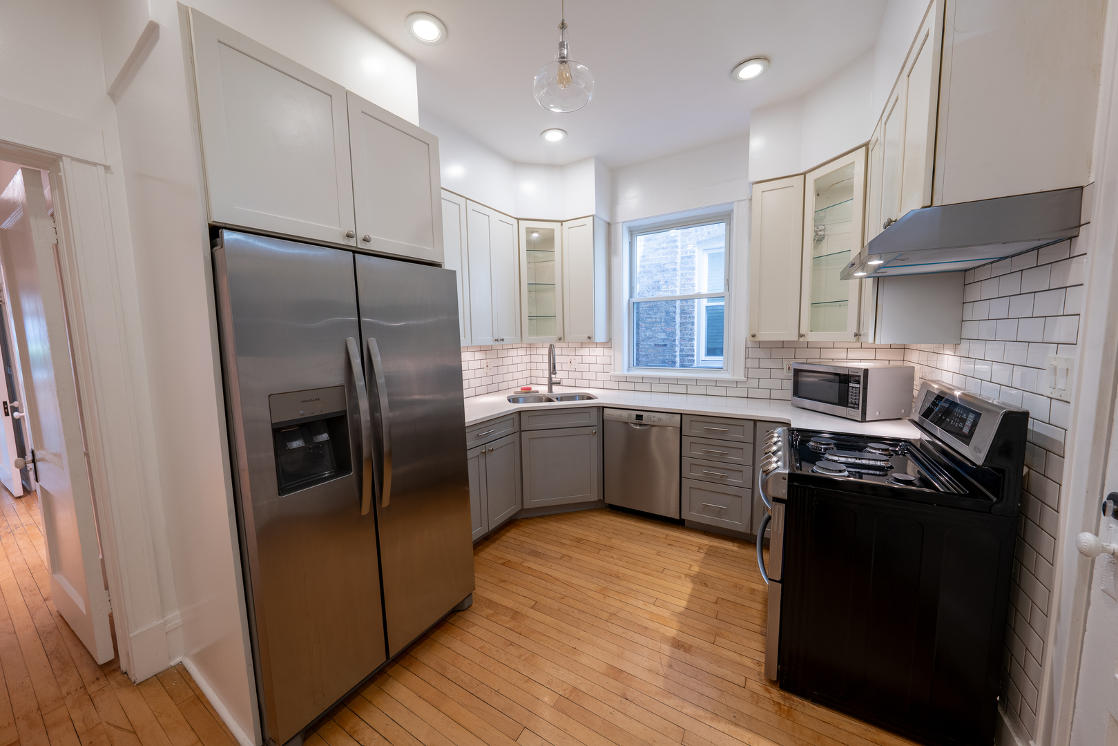 1460 West Foster Avenue, Unit 1 Chicago, IL 60640 - Photo 8 of 14 a kitchen with stainless steel appliances a refrigerator a sink cabinets and wooden floor