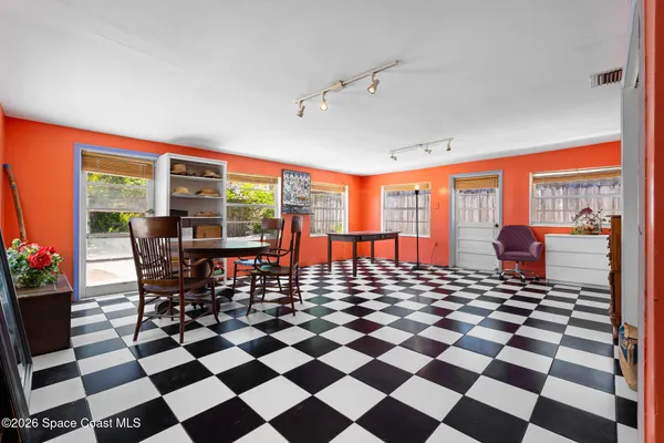 a room with a black white checkered floor with a gaming machine and dining chairs