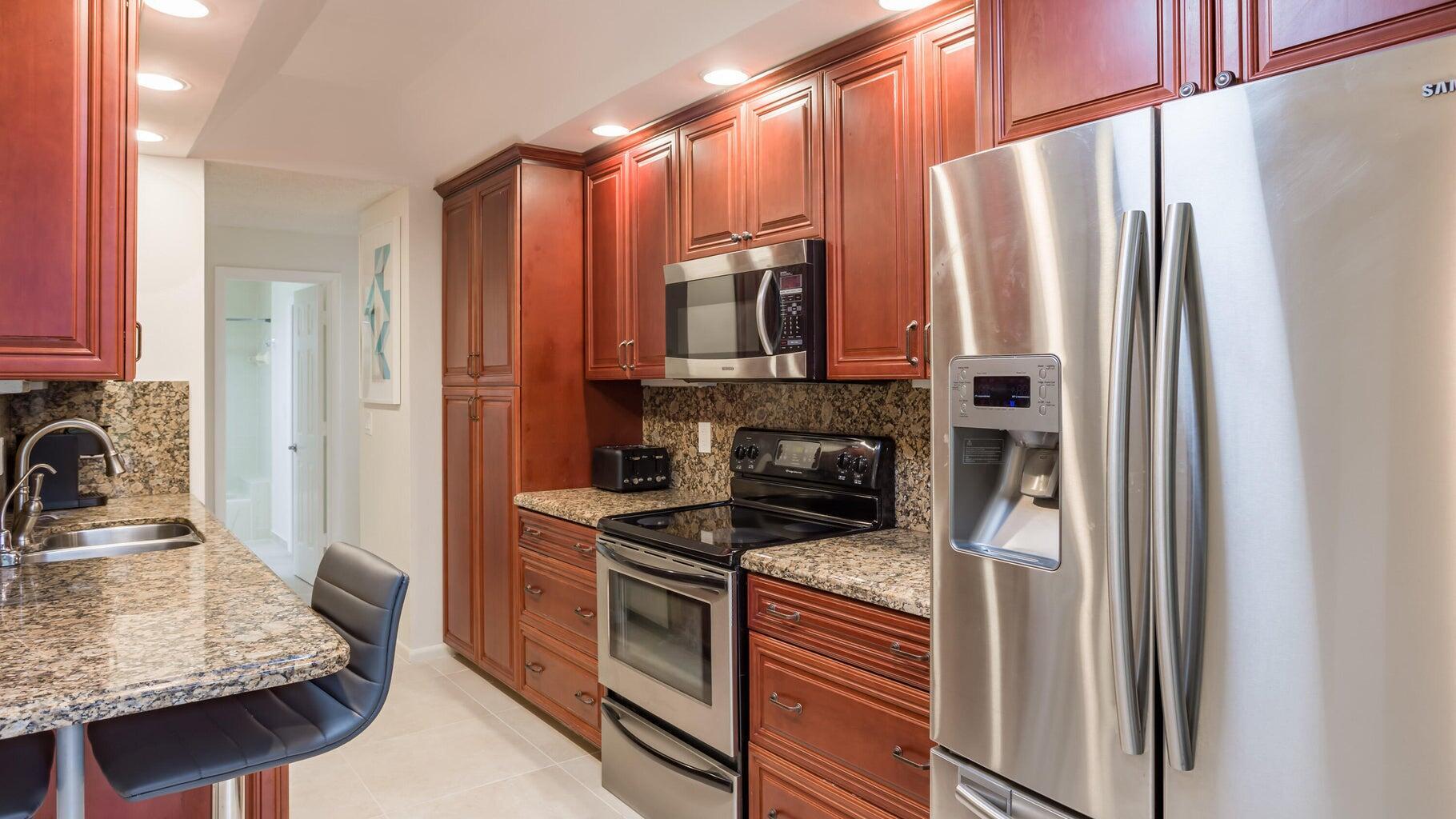 7460 La Paz Boulevard, Unit 208 Boca Raton, FL 33433 - Photo 9 of 23 a kitchen with stainless steel appliances granite countertop a refrigerator stove and sink