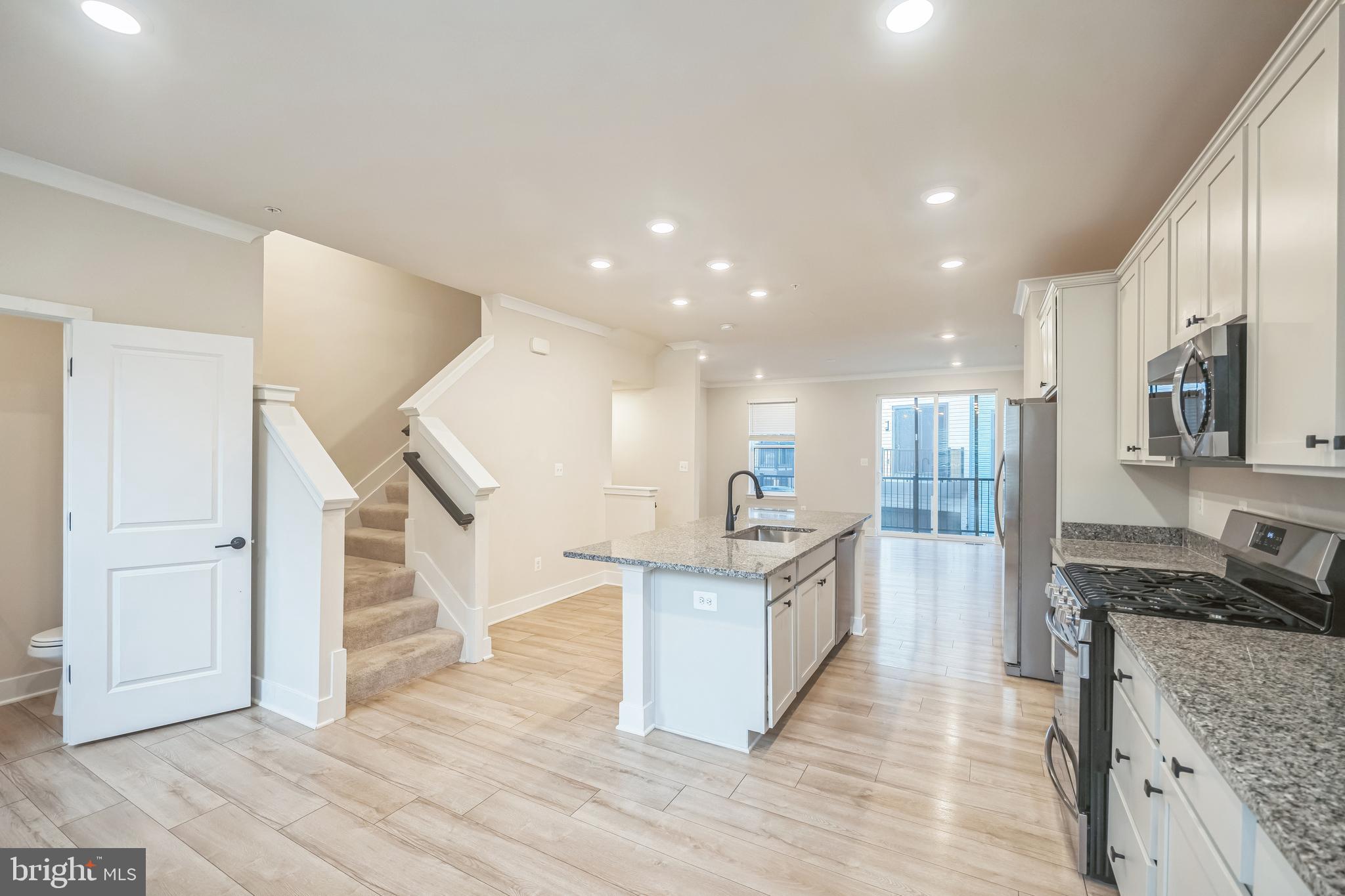 4402 Roland Heights Avenue Baltimore, MD 21211 - Photo 14 of 47 a kitchen with stainless steel appliances kitchen island wooden floors and white cabinets