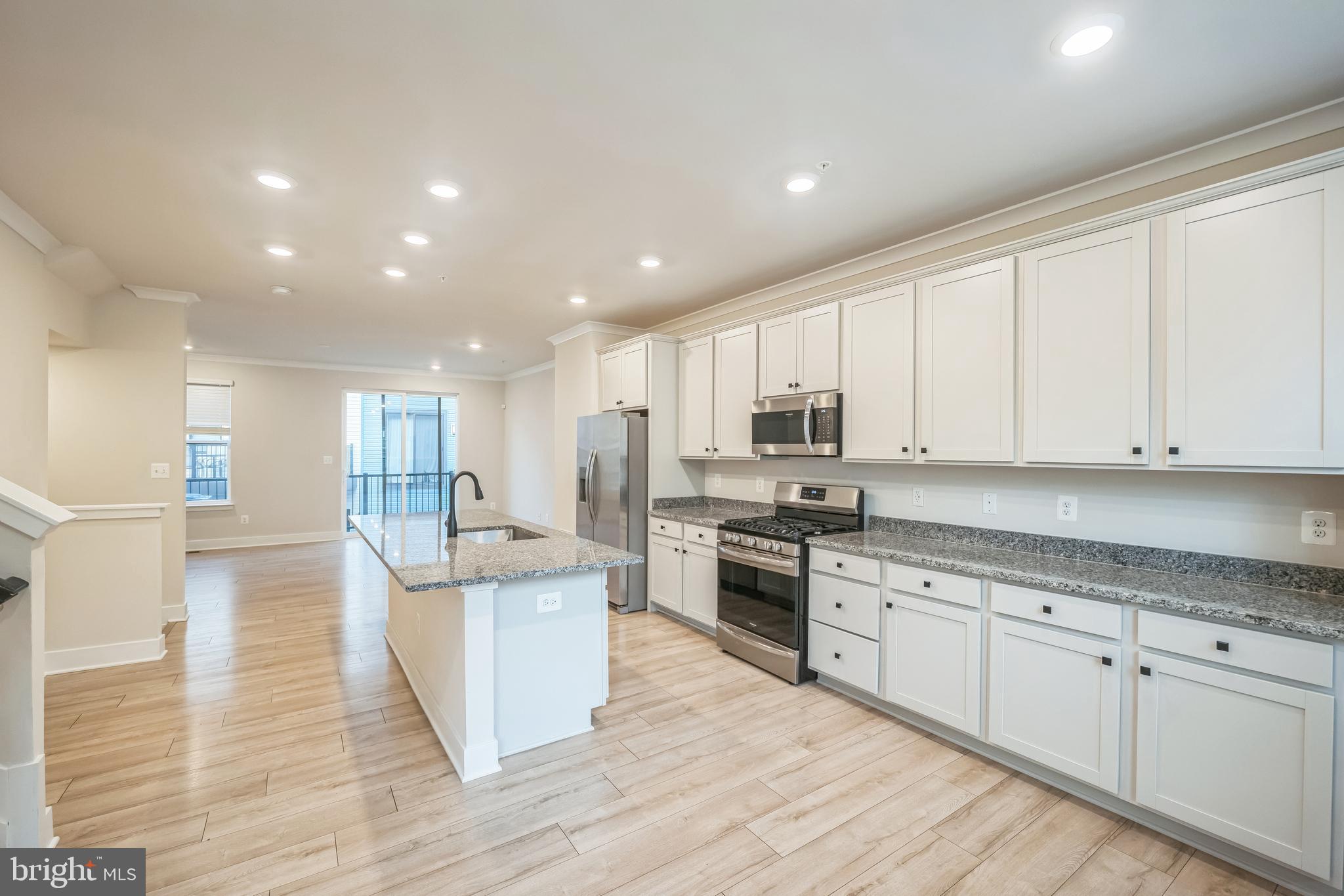 4402 Roland Heights Avenue Baltimore, MD 21211 - Photo 15 of 47 a large kitchen with stainless steel appliances granite countertop a stove a sink a refrigerator and white cabinets with wooden floor