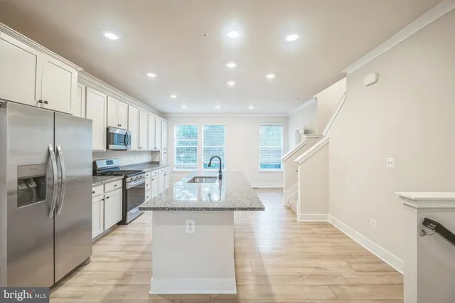 a large kitchen with stainless steel appliances granite countertop a refrigerator a stove and a sink