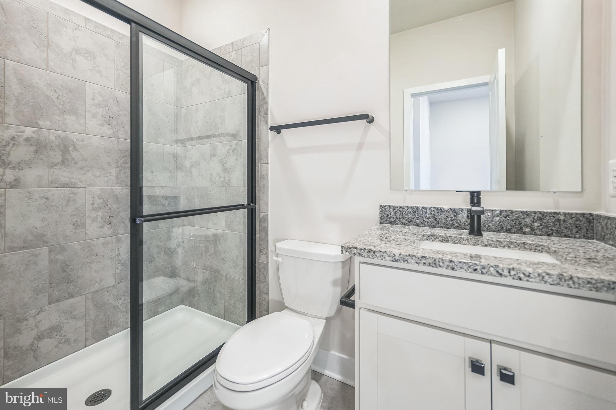 4402 Roland Heights Avenue Baltimore, MD 21211 - Photo 26 of 47 a bathroom with a granite countertop sink toilet a mirror and shower