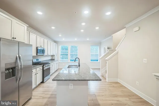 a kitchen with stainless steel appliances granite countertop a sink a stove and a refrigerator